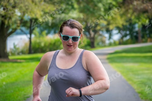 Preview: Young millennial woman tracking active fitness on smart watch while running