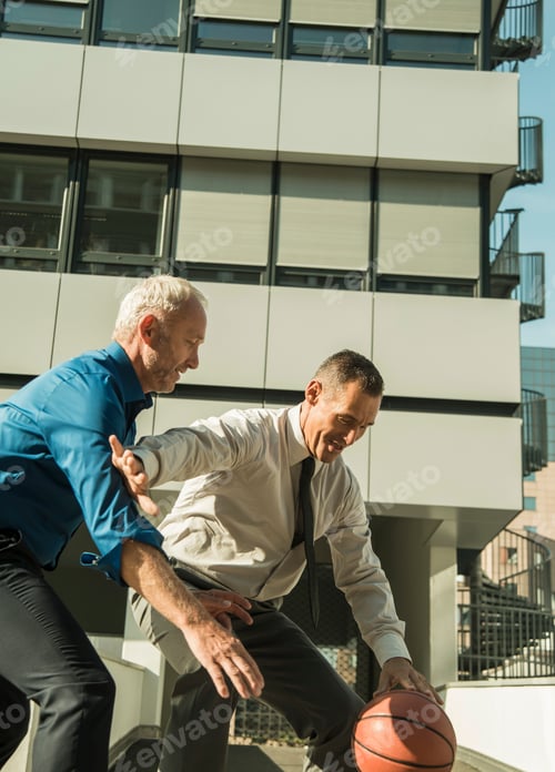 Preview: Two businessmen playing basketball outside office building