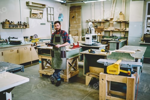 Preview: Confident joiner with notebook in workshop