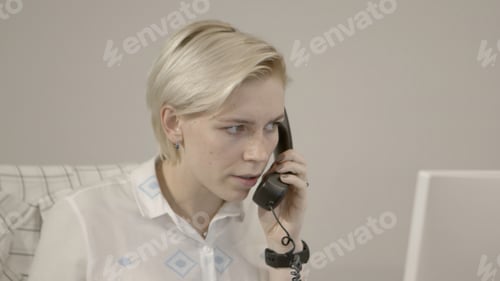 Preview: A woman at work. Stock footage. A cute secret in a shirt is talking on the phone and looking at the