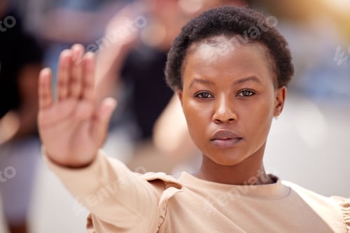 Preview: A tower of power and strength. Shot of a young woman holding her hand up to stop at a protest.