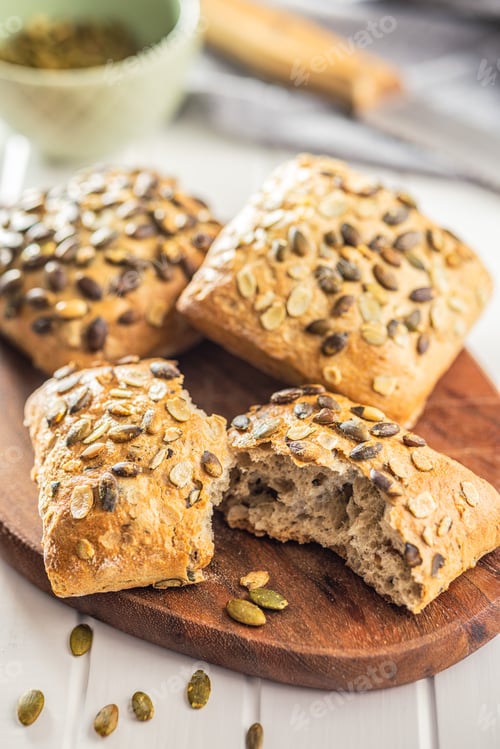 Preview: Whole grain bun with pumpkin seeds on cutting board.