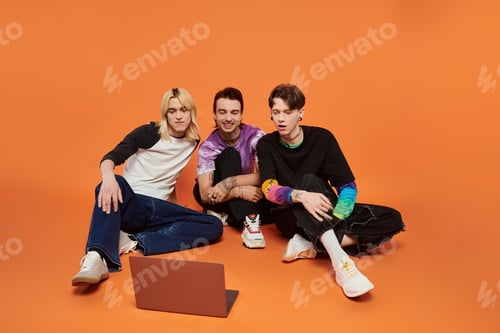 Preview: Queer friends in stylish attire watch a laptop