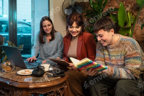 Preview: Diverse group of women and non-binary person collaborating in cozy cafe