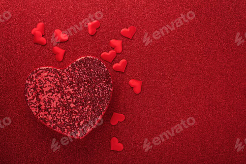 Preview: Red openwork gift boxes in shape of heart with small red decorative hearts on red background. Top vi