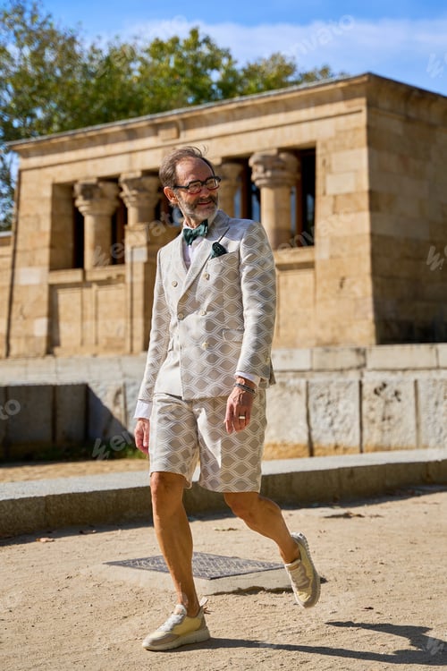Preview: Man in patterned suit and shorts walking near ancient stone temple outdoors
