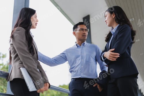 Preview: Businessman mediating between two arguing businesswomen in office building