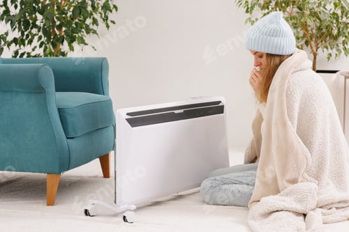 Preview: Frozen young woman with plaid warming near radiator at home