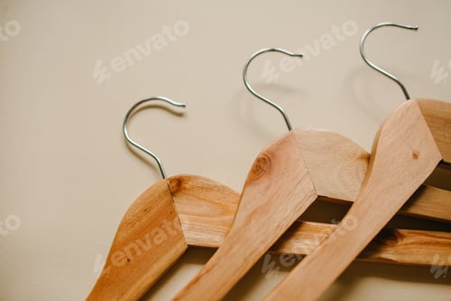 Preview: Three empty wooden hangers on beige background. Overhead view