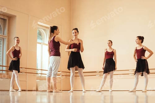 Preview: Ballet teacher talking with ballerinas during a class at dance studio.