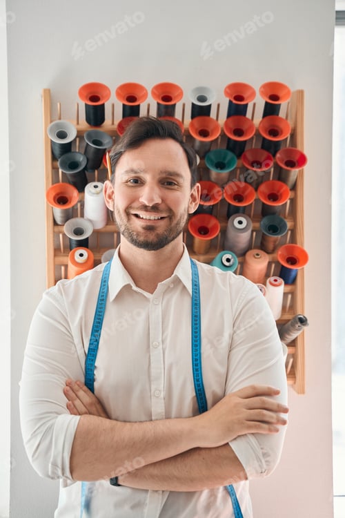 Preview: Cheerful dressmaker at stand with colourful thread