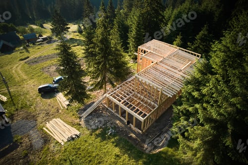Preview: Wooden frame house under construction near forest.