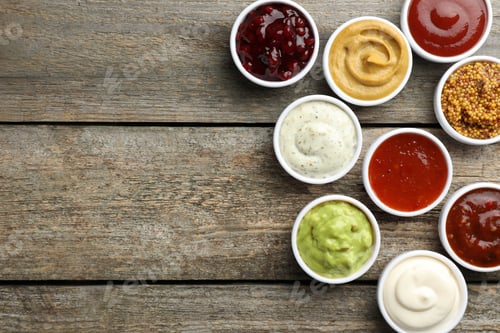 Preview: Different tasty sauces in bowls on wooden table, flat lay. Space for text
