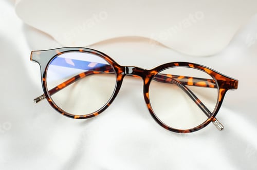 Preview: Leopard glasses on white silk fabric, close-up. Stylish women's glasses in a leopard-colored frame
