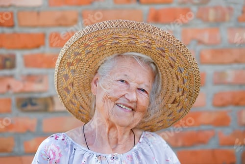 Preview: Senior woman portrait, on red brick wall background with white hair.
