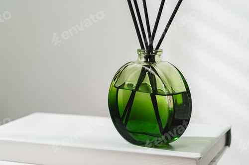 Preview: Aromatic Reed Diffuser on White Books With Shadows Playing on the Wall