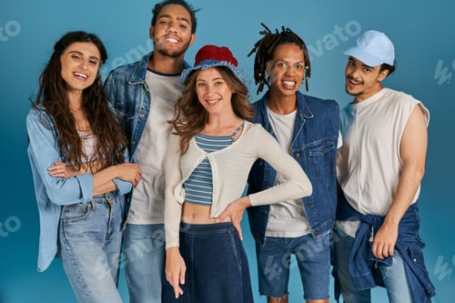 Preview: group portrait of interracial friends in casual wear smiling at camera on blue, street fashion