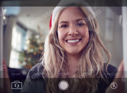 Preview: View From Behind Mobile Phone Screen As Woman Takes Christmas Selfie At Home