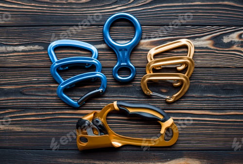 Preview: Creative design. Isolated photo of climbing equipment. Parts of carabiners lying on the wooden table