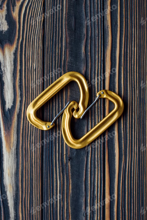 Preview: Good lighting. Isolated photo of climbing equipment. Parts of carabiners lying on the wooden table