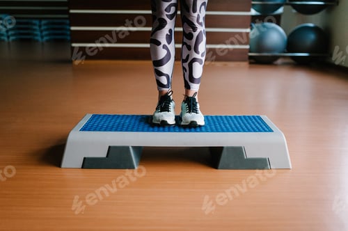 Preview: Young fitness girl in sportswear and shoes, standing legs on the Step platform. Woman feet on