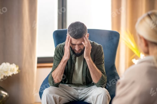 Preview: Man suffering from headache while having psychoanalysis