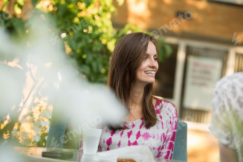 Preview: A woman sitting at a table in a garden.