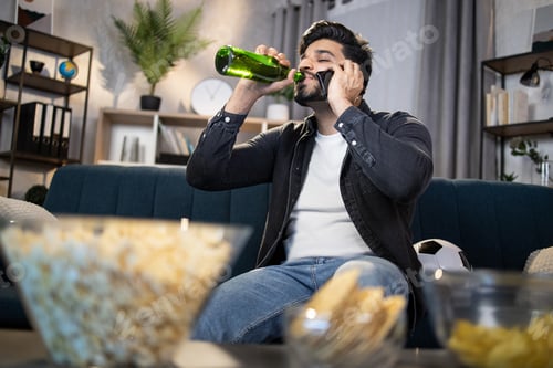 Preview: Muslim guy with smartphone and beer watching football