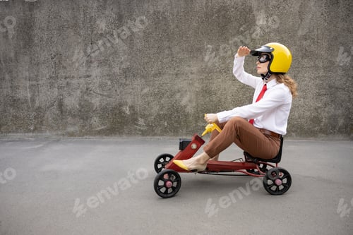 Preview: Funny businesswoman driving retro pedal car outdoor