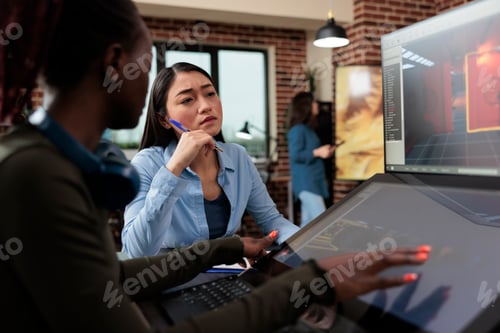 Preview: Multiethnic creative game creators sitting at desk with multiple displays while working with 3D