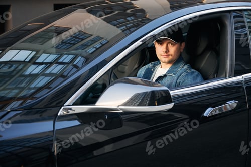 Preview: Handsome young man sitting in electric car.