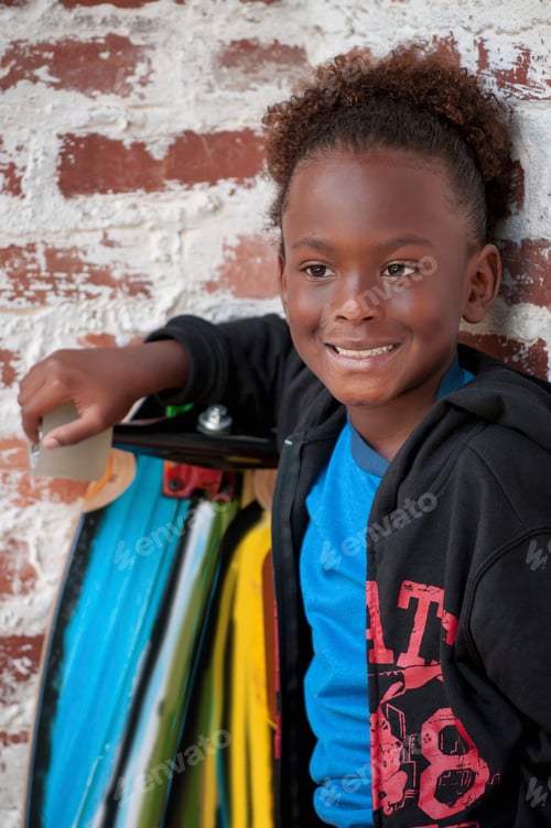 Preview: Portrait of young boy outdoors, holding skateboard, smiling