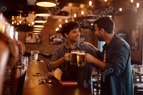 Preview: Happy man and his friend toasting while drinking beer in a bar.