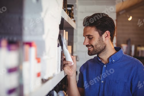 Preview: Male hair dresser selecting shampoo from shelf