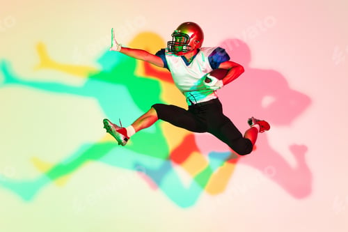 Preview: American football player isolated on gradient studio background in neon light with shadows