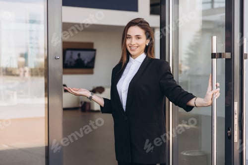 Preview: Saleswoman inviting customers inside new car dealership