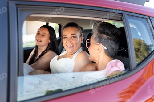Preview: Bride and friends smiling inside car on wedding day