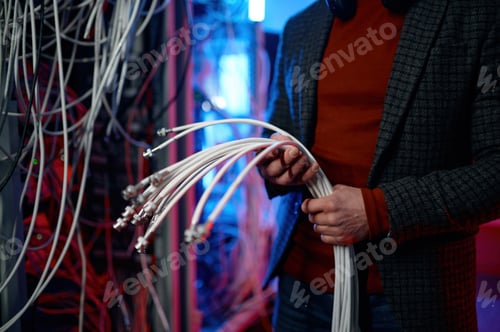 Preview: IT man with bunch of cables in hands in server room