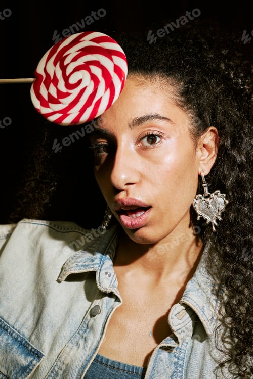 Preview: Portrait of Young Adult Middle Eastern Woman Posing with Large Lollipop in Photo Booth