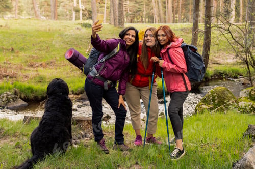Preview: Three women with hiking backpacks and a dog taking a selfie whil