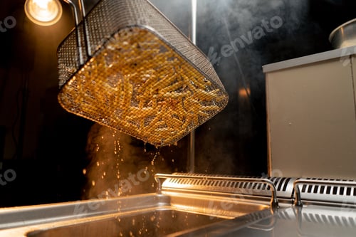 Preview: kitchen in the hotel restaurant the chef takes out delicious french fries from the fryer oil drips