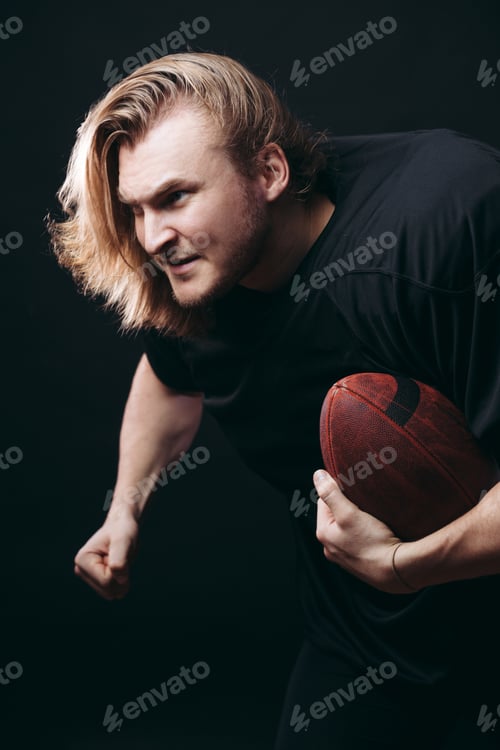 Preview: Determined American football player in action isolated on black background