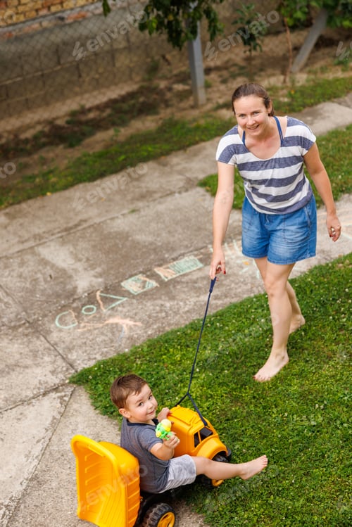 Preview: Mother having fun pushing child in toy truck