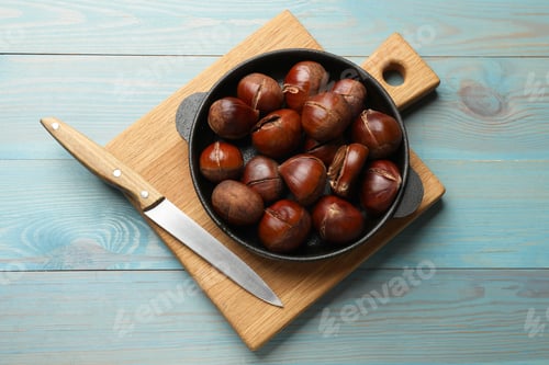 Preview: Fresh edible sweet chestnuts in frying pan on light blue wooden table, top view