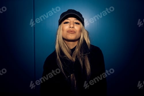 Preview: Caucasian attractive woman in black grunge attire posing against a blue wall
