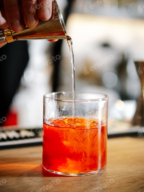 Preview: Bartender making Negroni cocktail on bar counter
