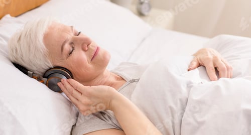 Preview: Calm senior woman in headphones enjoying audiobook