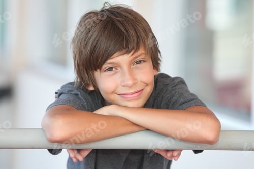 Preview: Smiling Preteen Boy Resting Arms on Metal Railing Outdoor