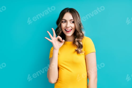Preview: Pretty smiling woman showing OK sign with fingers and tongue out