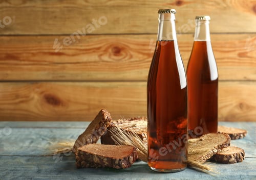Preview: Bottles of delicious fresh kvass, spikelets and bread on blue wooden table. Space for text